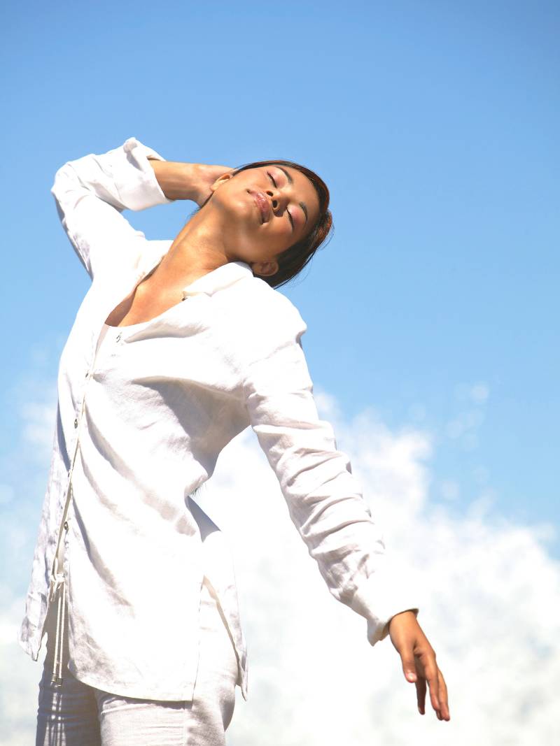 Femme yeux fermés face au ciel — retrouver son corps en sérénité